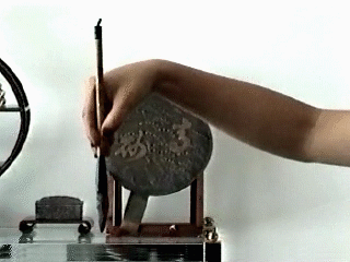 The brush held between the index and middle fingers, the thumb against it, the hand cupped.