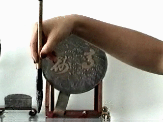 A closer view: the brush between the middle and index fingers, held in place by the thumb.